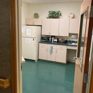 A view into a kitchen area with cabinets, appliances, and a green floor.