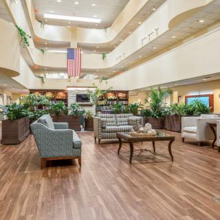 A spacious lobby with comfortable seating, plants, and a prominent flag hanging from the ceiling.