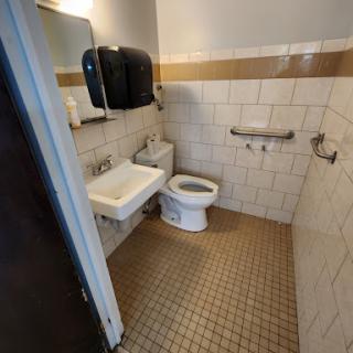 A tidy and functional bathroom featuring a toilet and sink, equipped for public use.
