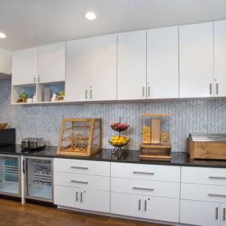A modern kitchen with white cabinets, appliances, and open shelves displaying dishes.