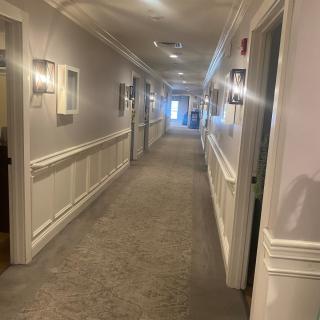 A well-lit hallway with several doors and carpeted floor.