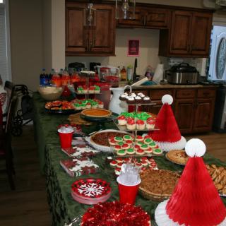 A kitchen table filled with Christmas-themed food and decorations for a holiday party.