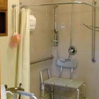 An accessible bathroom with a shower chair and grab bars for safety.