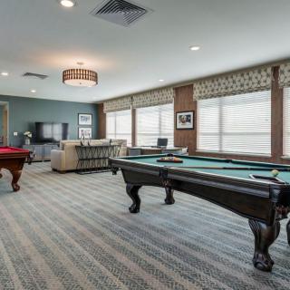 A spacious game room featuring multiple pool tables and a comfortable seating area.