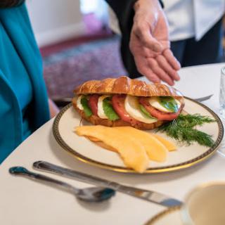A beautifully arranged croissant sandwich with fresh vegetables and cheese on a plate, ready to be enjoyed.