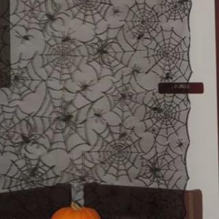 A Halloween-themed decoration featuring a pumpkin and a backdrop of spider webs with fake spiders.