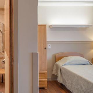 A minimalist bedroom with a single bed and wooden furniture.
