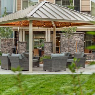 A cozy outdoor gazebo with comfortable seating surrounded by a well-maintained lawn.