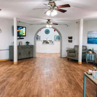A spacious lobby with a wooden floor, ceiling fans, and comfortable seating.