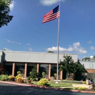 An American flag flying in front of a building on a clear day.