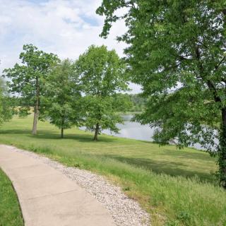 A scenic pathway through a lush park with trees and a view of a lake.