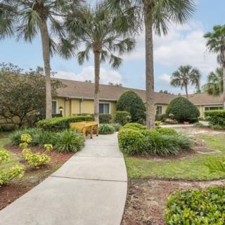 A well-maintained home with lush landscaping and palm trees lining the pathway.