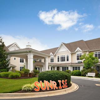 A large, elegant building with well-maintained gardens and a clear blue sky in the background.