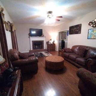 A cozy living room with leather sofas, a central coffee table, and a fireplace beneath a mounted television.