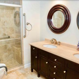 A modern bathroom featuring a dual-sink vanity with two round mirrors and a glass-enclosed shower.