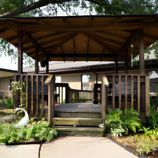 A wooden gazebo surrounded by lush plants in a garden setting.