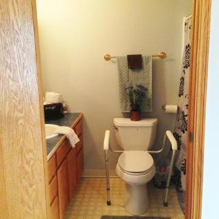 Small bathroom with a toilet and grab bars for accessibility.