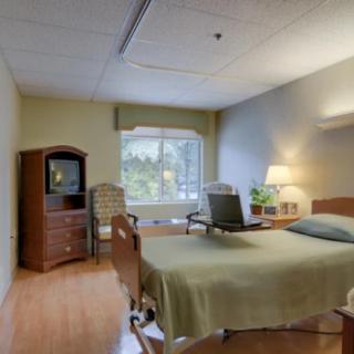 A hospital room with a bed, television, and seating area.