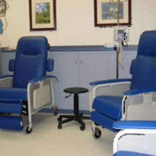 A healthcare facility room with blue medical chairs and equipment.