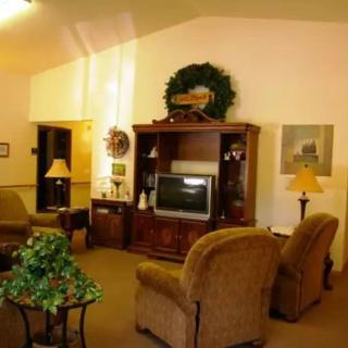 A cozy living room featuring a television, comfortable chairs, and decorative elements.