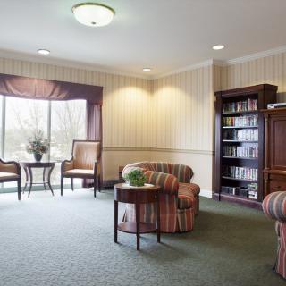 A cozy living room with comfortable seating, a bookshelf, and ample natural light.