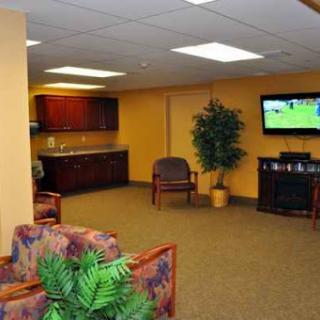 A cozy waiting area with comfortable seating, a TV, and decorative plants.
