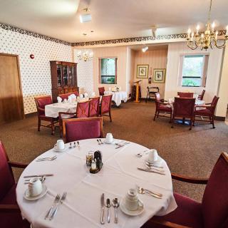 Elegantly set dining room with round tables and upholstered chairs, ready for guests.