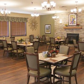 A cozy dining room with elegantly arranged tables and chairs, warm lighting, and tasteful decor.