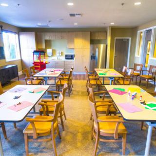 A brightly lit classroom with tables set up for arts and crafts activities.
