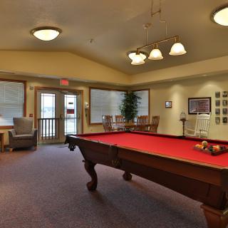 A cozy game room featuring a red pool table and comfortable seating.