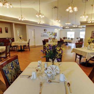 A spacious dining room with elegant table settings and decorative lighting.