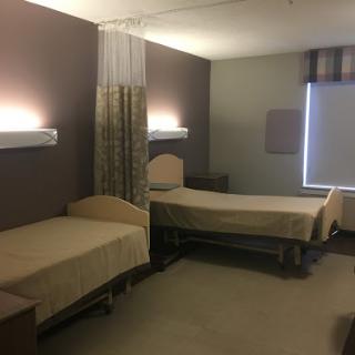 A well-lit hospital room featuring two beds set up for patient care.