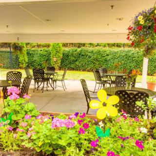 A charming outdoor patio area with tables and chairs surrounded by vibrant flowers and greenery.