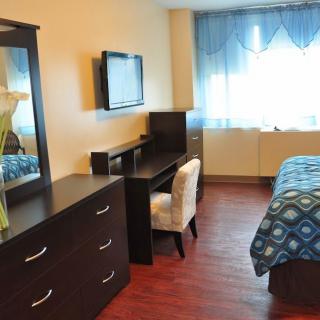 A neatly organized bedroom with modern furniture and a television.
