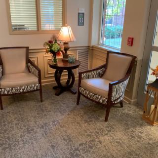 A cozy lobby area with two upholstered chairs, a wooden side table, and ambient lighting.
