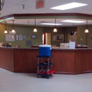 An office reception area with a cleaning cart in front of the desk.