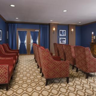 A cozy home theater room with patterned red chairs and blue walls.