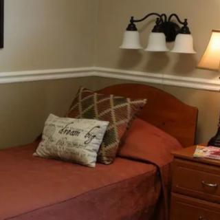 A cozy bedroom with a neatly made bed, pillows, and two lamps on the nightstand.