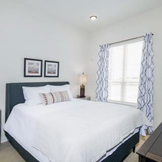A modern bedroom with a white bedspread and stylish decor.