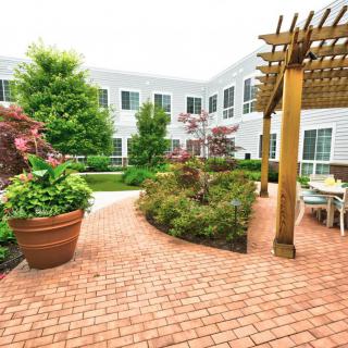 A beautifully landscaped courtyard with a brick pathway, pergola, and vibrant greenery.