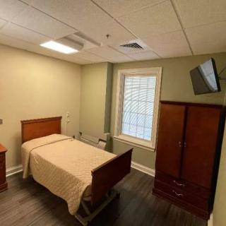 A minimalist bedroom with a single bed, wardrobe, and wall-mounted television.