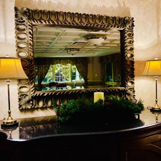 An elegant interior scene featuring a beautifully framed mirror, soft lighting from lamps, and tasteful decor.