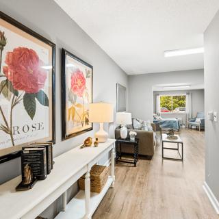 A modern hallway with floral artwork, a console table, and stylish furniture in a well-lit living space.