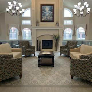 A spacious living room with a fireplace, comfortable seating, and elegant chandeliers.