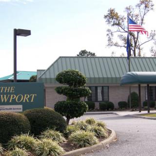 The Newport entrance with a well-maintained landscape and an American flag.