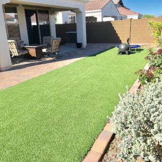 A well-maintained backyard featuring artificial grass, outdoor seating, and a pleasant atmosphere.