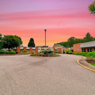 A serene view of a landscaped entrance at sunset, showcasing vibrant colors in the sky.