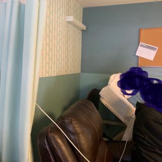 A waiting area in a clinic with a curtain, couch, and bulletin board.