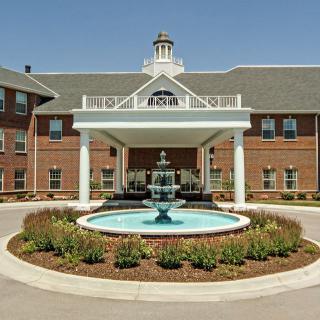 A hotel entrance featuring a central fountain surrounded by landscaped gardens.