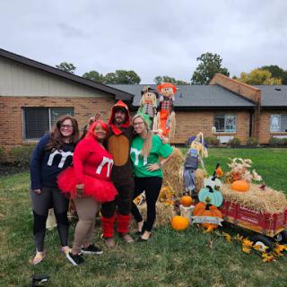 A fun group dressed in festive costumes, celebrating the fall season with pumpkins and decorations.